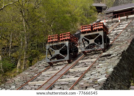 Two trolleys with crates of cut slate on rails on a steep slate made incline.