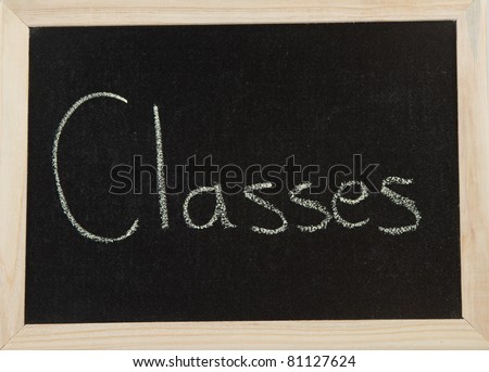 A black board with a wooden frame and the word \'CLASSES\' written in chalk.
