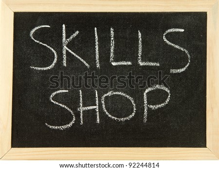 The words \'SKILL SHOP\' hand written in white chalk on a black board with a wooden frame.
