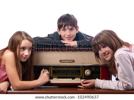 Three teenage friends listening to music on the old radio isolated on white.