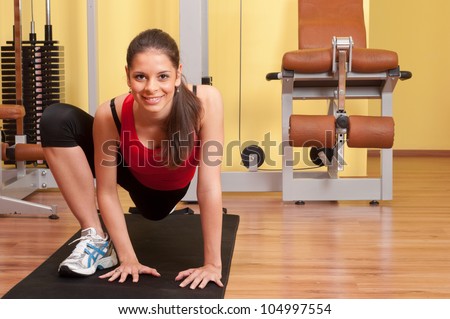 Beautiful young woman exercising in the gym on the floor.