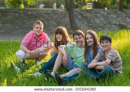 Happy teenage friends spending time together in the park on sunny summer day.