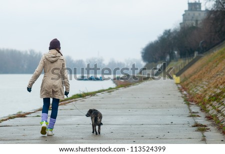 Teenage girl walking the dog on cloudy autumn day.