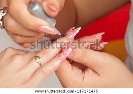 Manicure process in beauty salon showing making of beautiful drawings on artificial nails.