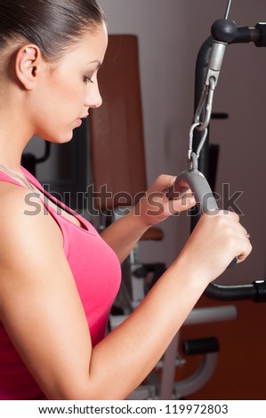 Beautiful young woman exercising arms in health club.