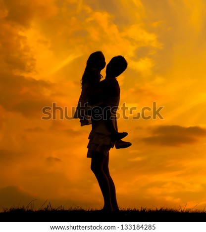 Silhouettes of mother and daughter hugging on beautiful spring day.