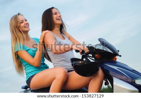 Two beautiful girls enjoy motorcycle ride at summer.