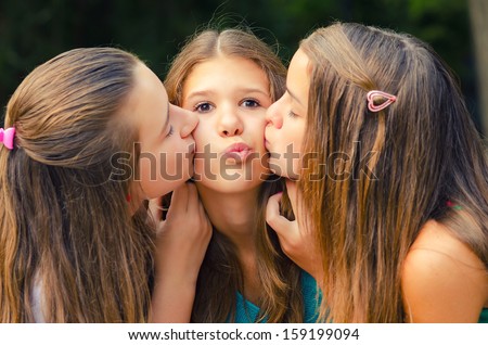 Teenage girl kissed on the cheeks by her friends.