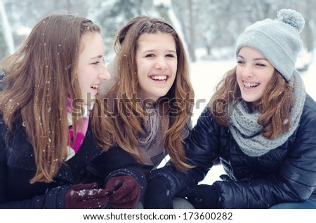 Three teenage girls having fun in the snow on cold winter day.