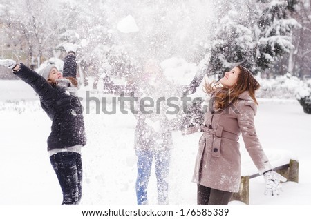 Three teenage girls throwing snow in the air on beautiful winter day.