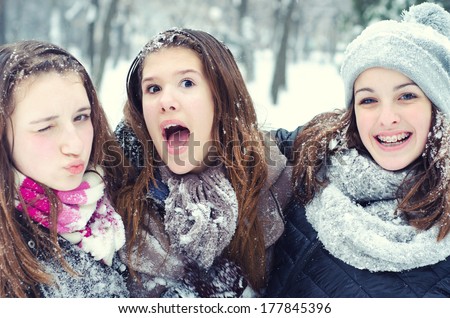 Three Teenage Girls Having Fun In The Snow On Cold Winter Day.