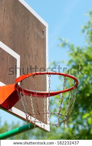Basketball hoop made of chains on outdoor basketball field.