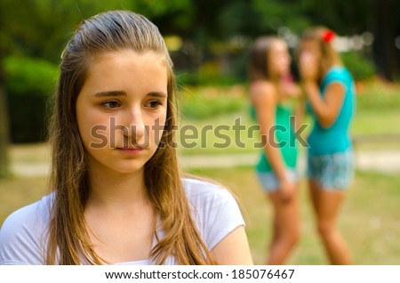 Two teenage girls making fun of the third on beautiful summer day.