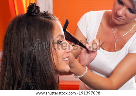 Hairdresser making hair of beautiful smiling teenage girl.