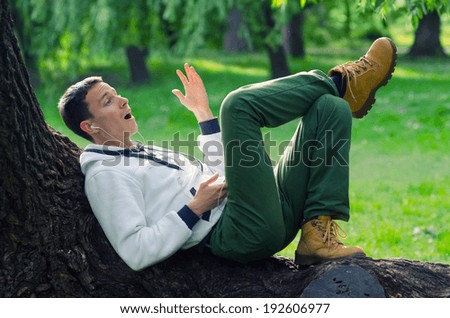 Young man listening to the music in the park on sunny spring day.