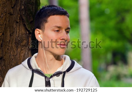 Young man listening to the music in the park on sunny spring day.