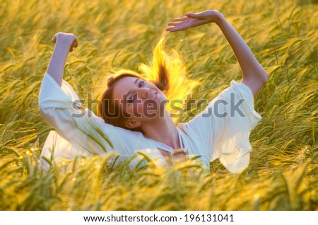 Beautiful woman having fun in the wheat field on sunny summer day.