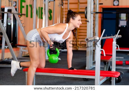Beautiful young fitness girl lifting weights in the modern gym.