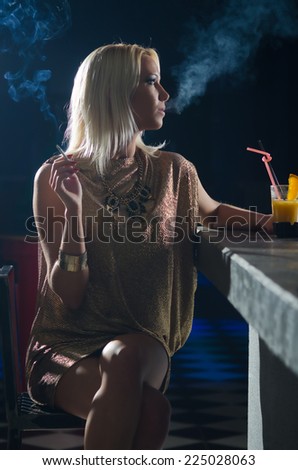 Beautiful elegant lady sitting alone in the night club and smoking cigarette.