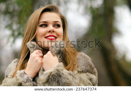 Beautiful glamorous lady having fun outdoor on gloomy winter day.