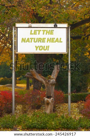 Let the nature heal you billboard sign in front of the autumn park.