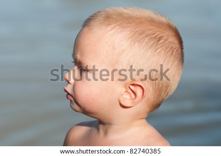 Little boys profile while standing in the water on the hot summer day.