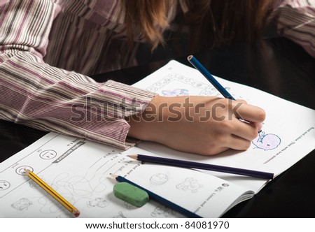 Teenage girls hand holding pencil and doing her homework.