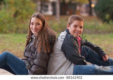 Teenage boy and girl enjoying each others company in the park on beautiful autumn day.
