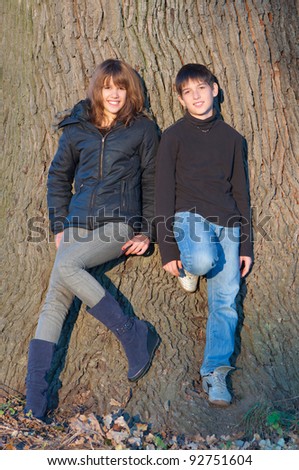 Teenage boy and a girl enjoying each others company on sunny autumn day.