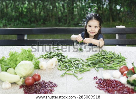 Little girl cleaning peas and recommend you to eat healthy food