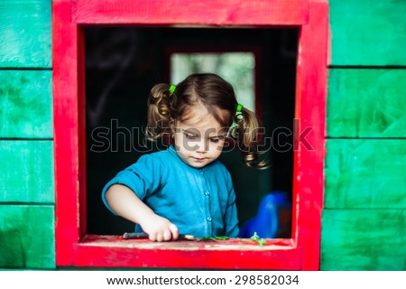 Little girl playing in wooden house  in nature