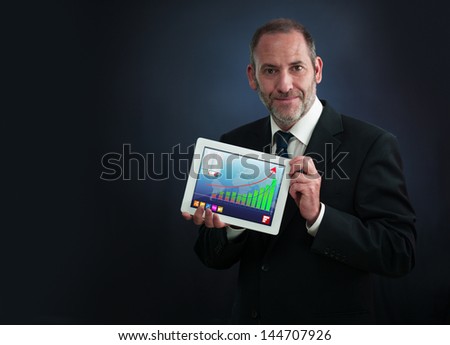 a mature businessman or salesman shows his Tablet PC with positive chart