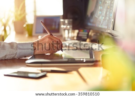Graphic Designer working with interactive pen display, digital Drawing tablet and Pen on a computer. Smooth tracking shot with nice backlit lensflare.