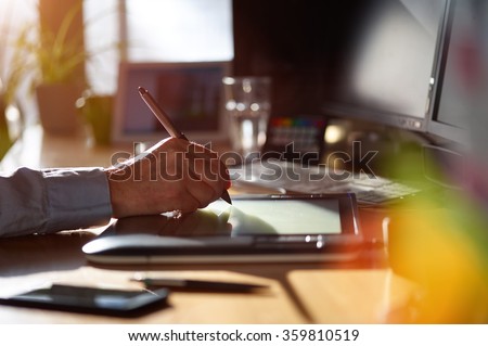 Graphic Designer working with interactive pen display, digital Drawing tablet and Pen on a computer. Smooth tracking shot with nice backlit lensflare.