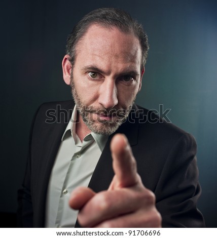 Portrait of mature businessman pointing at you over colored background