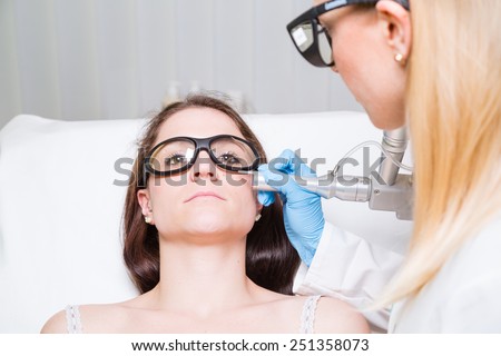 Removing mole from face of a young woman with medical laser.