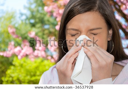 A young woman with a allergy sneezing into handkerchief.