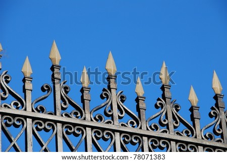 Close-up of a wrought iron fence over a blue sky