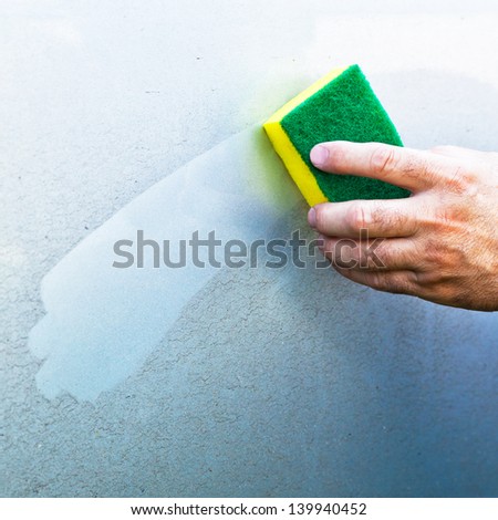 hand Cleaning car using a yellow cleaning sponge