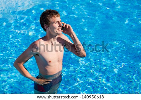 young man speaking on the phone and smiling in the swimming pool