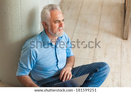 old man with notebook sitting on the floor