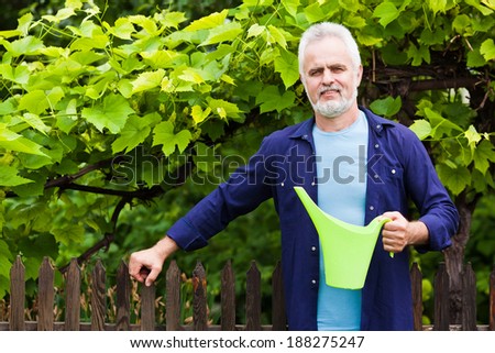 Portrait of senior man holding watering can