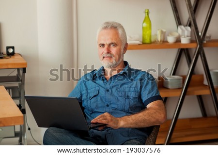 senior man with notebook sitting at the kitchen