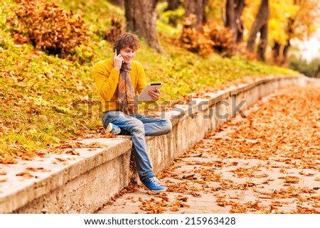 young man with tablet and speaking on the cell-phone in outdoor