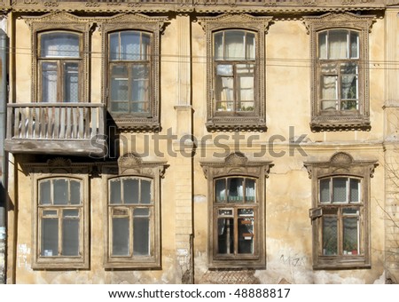 A fragment of the facade of old wooden houses with carved and casings on the windows. Russian style. Provincial architectural heritage.