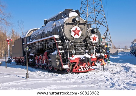 Steam locomotive beside a railway station platform. Winter. Retro train.