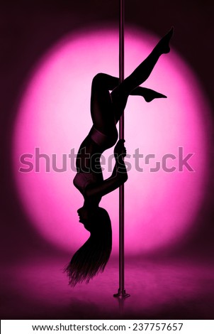 Silhouette of graceful girl dancing on pylon