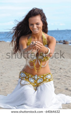 Beautiful woman in white dress play with sand (focus on hands)