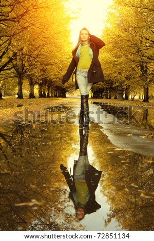 Woman at autumn walking on puddle