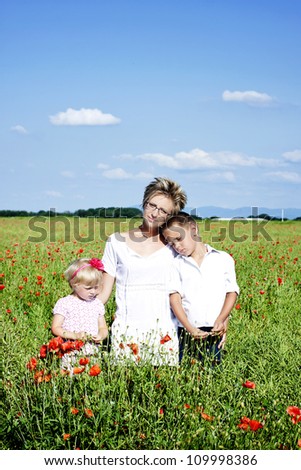 Portrait of cute family in poppy filed during hot summer day